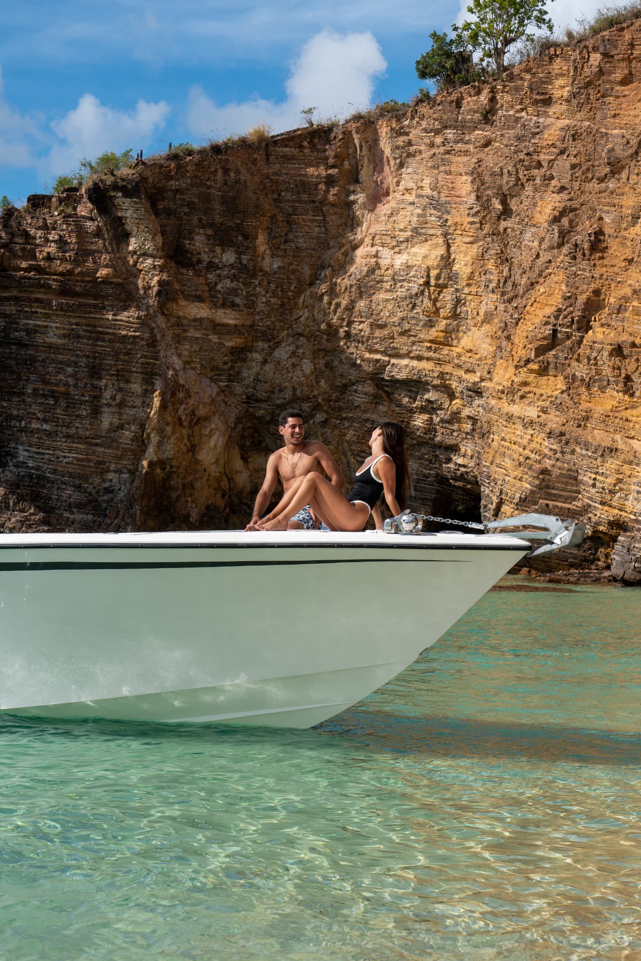 Guests relaxing on the bow beneath a Caribbean cliff